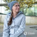 Frau mit hellgrauem Mantel und Strick-Mütze