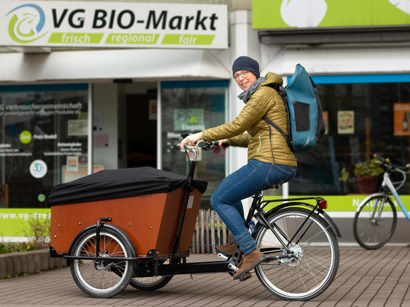 Frau fährt Lastenrad vor der VG