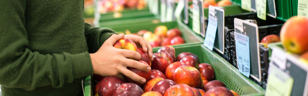 Hände greifen in eine Kiste voller Bio-Äpfel